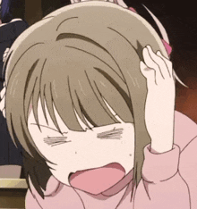 a girl in a pink sweater is holding her head with her hand .