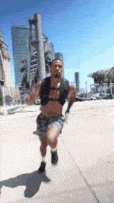 a man wearing a black vest is running on a sidewalk in a city