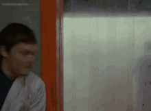a man in a white lab coat is standing in front of a window .