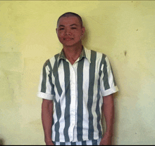 a man wearing a striped shirt stands in front of a wall
