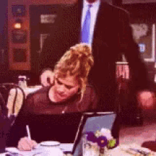 a man and woman are kissing while looking at a laptop .