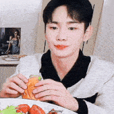 a young man is eating a sandwich with strawberries on it