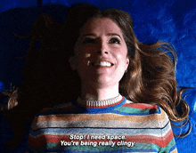 a woman in a striped sweater is smiling and laying on a blue cloth .