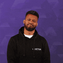 a man wearing a black hoodie with the word voxtur on the front