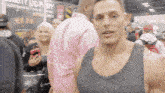 a man in a gray tank top stands in a crowd of people