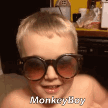 a little boy wearing sunglasses and the word monkeyboy on his face