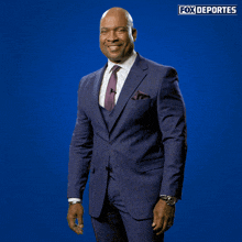 a man in a suit and tie is dancing in front of a blue background that says " fox deportes "