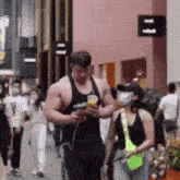 a man and a woman are walking down a street wearing masks .