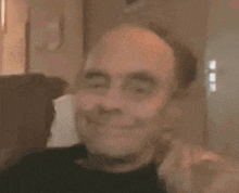 a man with a bald head is sitting in a chair and looking at the camera .