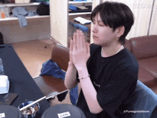 a man praying with a black shirt that says yume global team on it