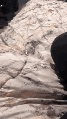 a person laying on a bed with a marble patterned comforter