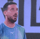 a man with a beard is wearing a blue shirt with a mizuno logo
