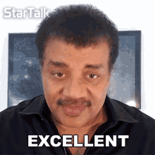 a man in a black shirt says excellent in front of a picture