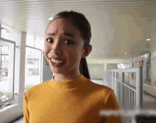 a woman wearing a yellow sweater is standing in a hallway