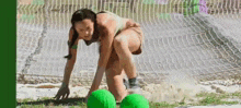a woman is bending over to pick up a green ball while playing soccer .