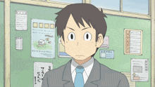 a man in a suit and tie is standing in front of a bulletin board with posters on it