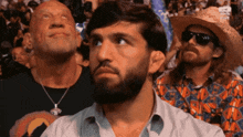 a man with a beard wearing a cowboy hat looks up at something