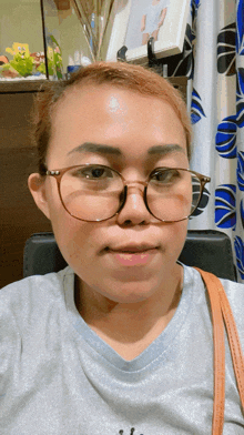 a woman wearing glasses is sitting in front of a picture