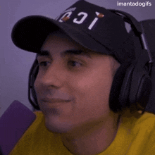 a man wearing headphones and a hat is smiling and looking up .