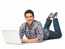the man is laying on the floor using a laptop computer .