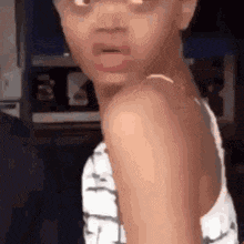 a little girl wearing glasses is making a funny face and looking at the camera .
