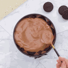 a person is scooping chocolate into a pan with oreos on top