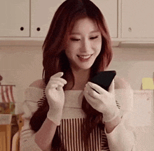 a woman wearing white gloves is holding a cell phone in her hands .