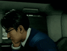 a man wearing glasses and a blue suit is sitting in a car