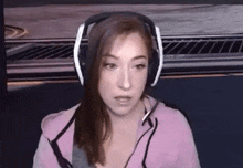 a woman wearing headphones and a microphone is sitting in front of a computer screen .