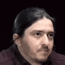 a man with long hair and a beard is making a face .