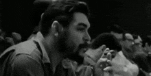a black and white photo of a man smoking a cigarette .