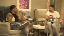 two men are sitting in chairs talking to each other .