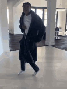 a man in a black robe and white socks is dancing in a room