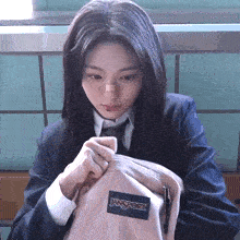 a girl in a school uniform is holding a jansport backpack