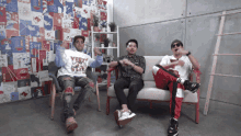 three men sit on a couch with one wearing a shirt that says yeet