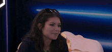a woman wearing sunglasses is sitting on a bed in a room .