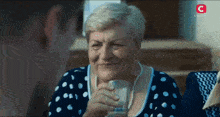 an older woman drinking from a glass with the letter c on the bottom