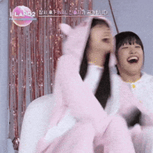 two girls are laughing and one of them is wearing a pink costume