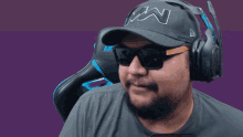 a man wearing sunglasses and headphones sits in a chair that says akracing