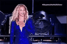 a woman in a blue dress is standing on a stage in front of a microphone .
