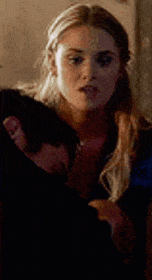 a woman is standing next to a man in a dark room and talking to him .