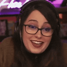 a close up of a woman wearing headphones and glasses smiling .
