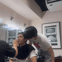 a man wearing a shirt that says " charity " is getting his makeup done