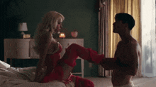 a man and a woman are having sex on a bed . the woman is wearing red thigh high stockings .