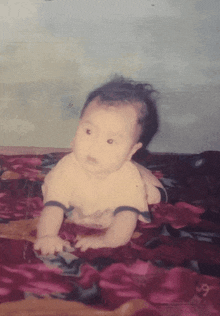 a baby laying on a blanket with the number 9 on the bottom right