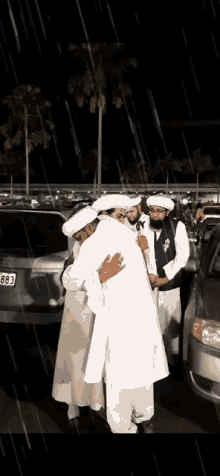 a man hugging another man in front of a car with the license plate 863