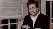 a man in a suit is standing in front of a window .