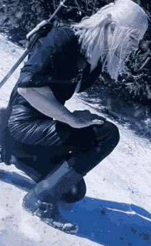 a person with white hair is kneeling in the snow