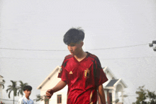 a boy wearing a red adidas jersey with the letter b on it