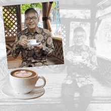 a man in a floral shirt is holding a cup of cappuccino